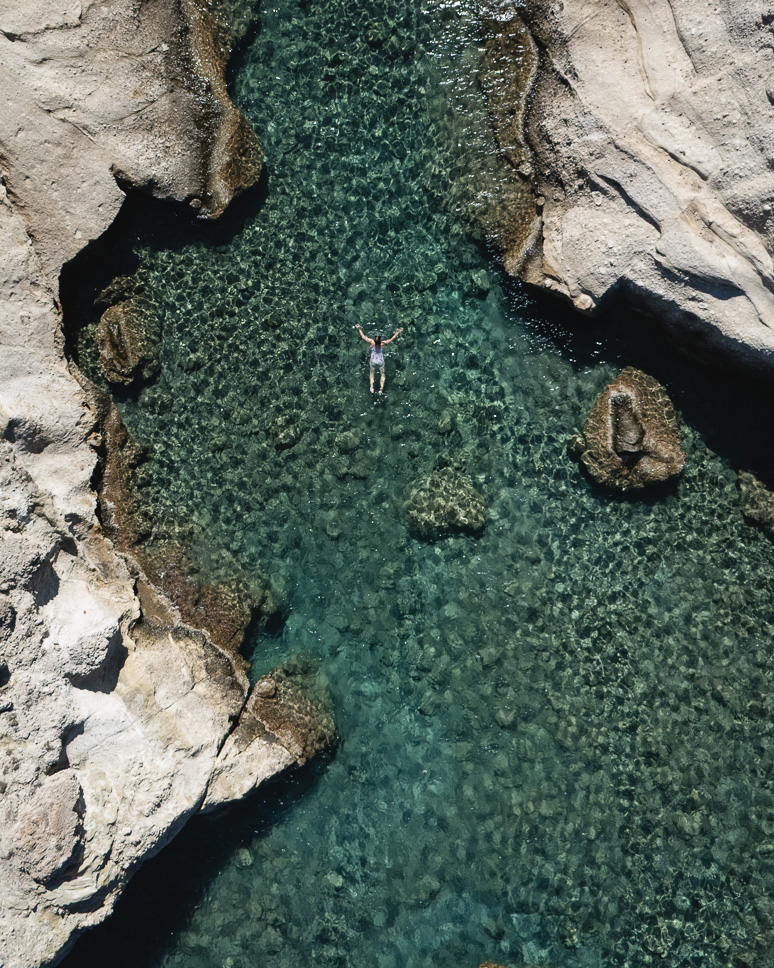 Drone shot of a swimming girl in Kleftiko beach Milos