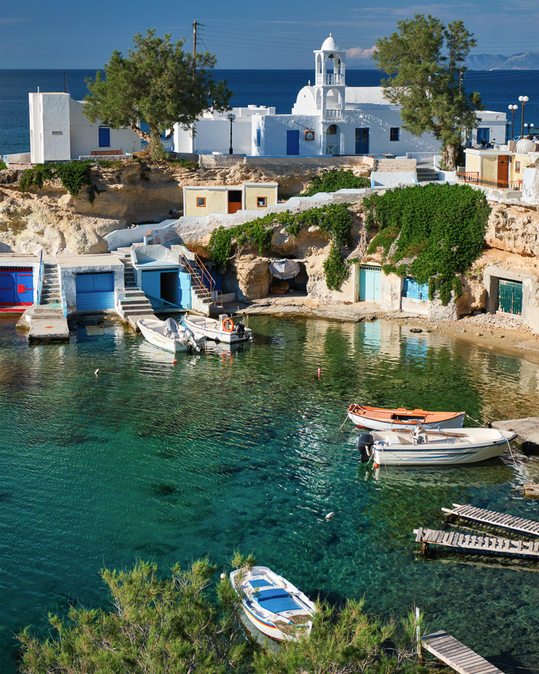 one of the beautiful villages in Milos; Typical Greece scenic island view - small harbor with fishing boats in crystal clear turquoise water, traditional white houses church. Mandrakia village, Milos island, Greece.