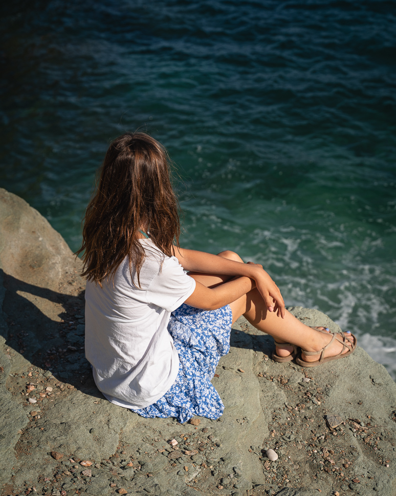Girl at Vitali Beach by the blue water in Andros